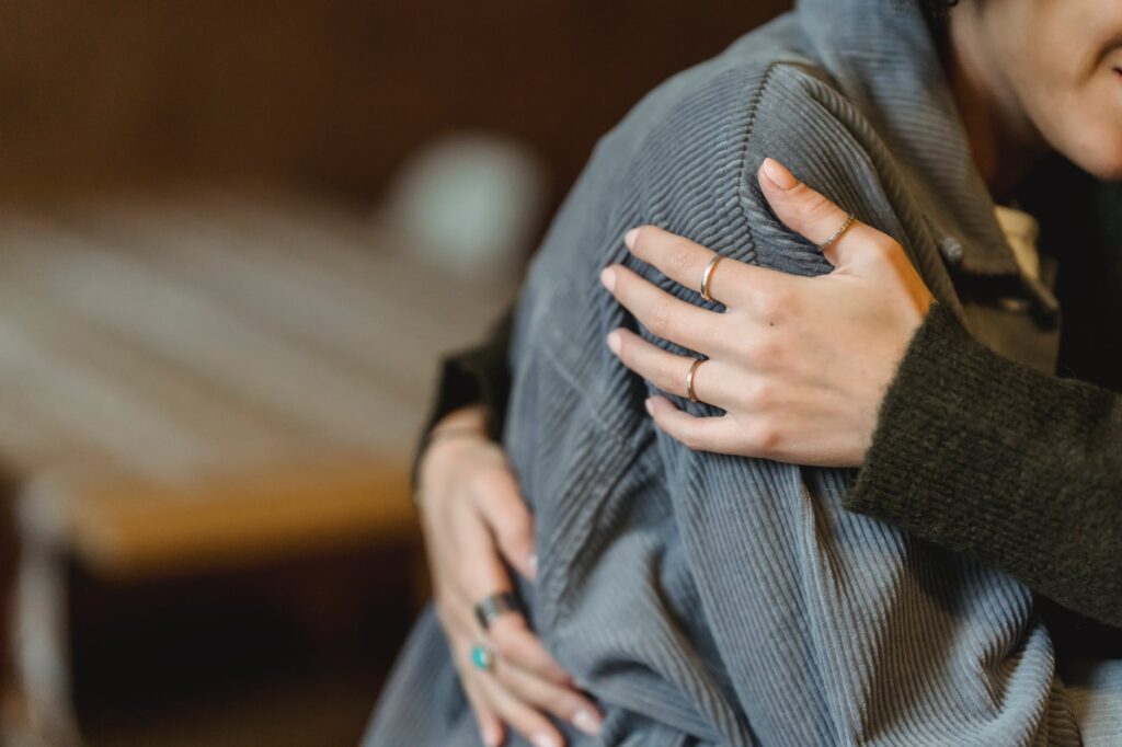 Close-up of couple hugging with visible engagement ring on woman's hand