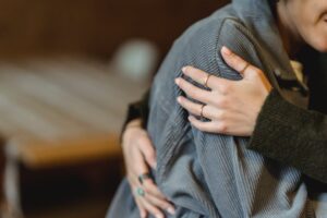 Close-up of couple hugging with visible engagement ring on woman's hand