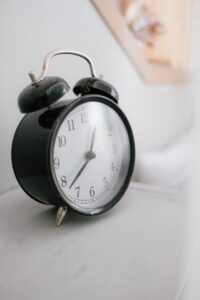 Classic black analog alarm clock on a white minimalist desk