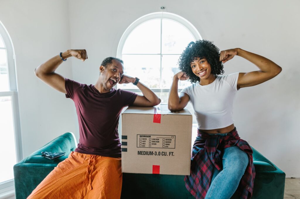 Happy couple celebrating while unpacking moving boxes in new home